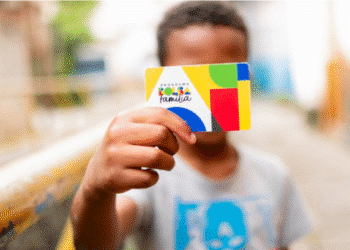 Criança segurando cartão do Programa Bolsa Família.