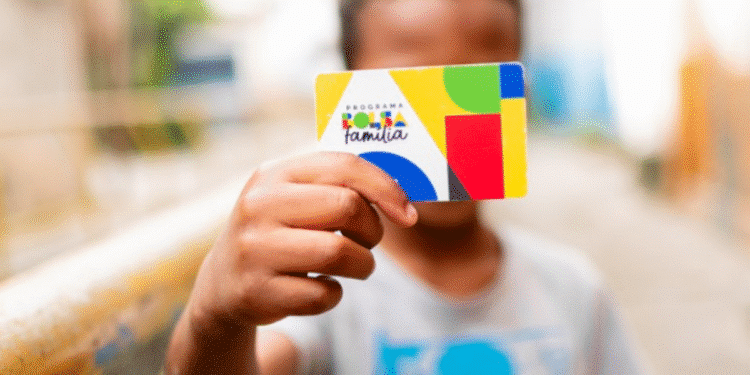 Criança segurando cartão do Programa Bolsa Família.