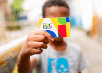 Criança segurando cartão do Bolsa Família com elementos gráficos coloridos.