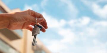 Mão segurando chave de casa, simbolizando acesso ao Auxílio Aluguel