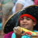 Criança com chapéu de pirata segurando spray em evento festivo ao ar livre.