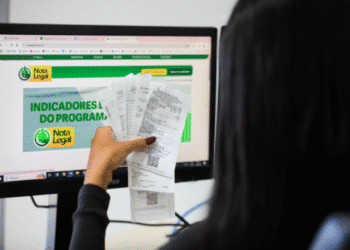 Pessoa verificando resultados no programa Nota Legal com diversos cupons fiscais