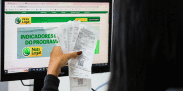 Pessoa verificando resultados no programa Nota Legal com diversos cupons fiscais