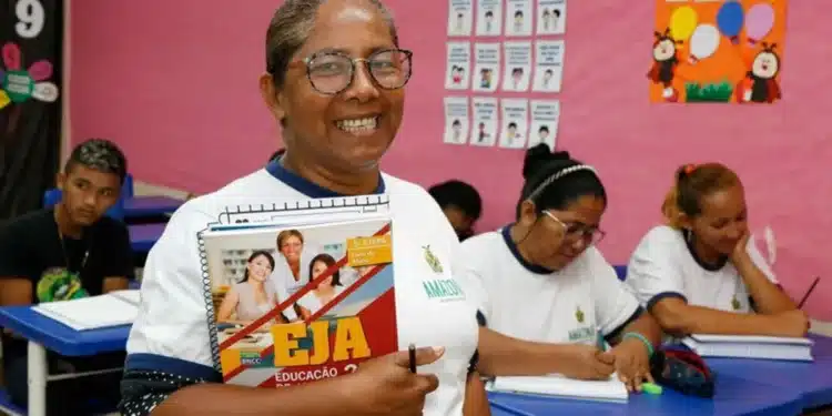 Aluna sorridente segurando caderno do EJA em sala de aula
