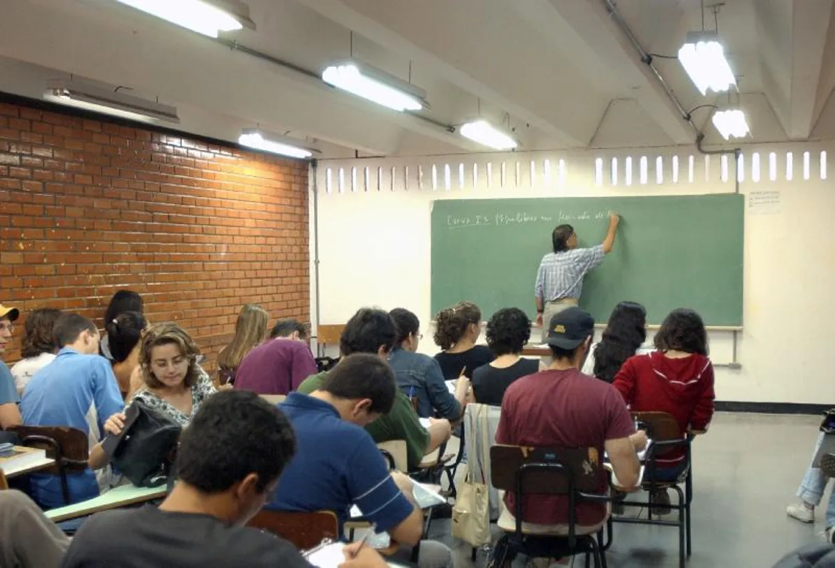 Alunos em sala de aula assistindo aula do professor no quadro