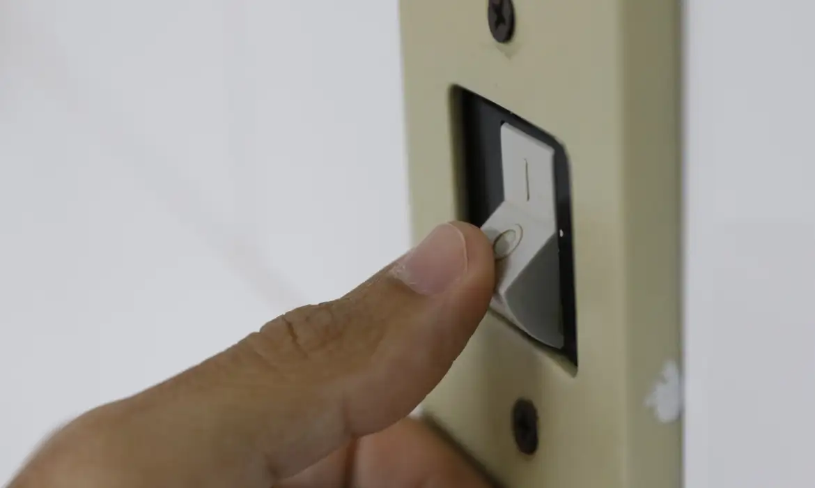 Pessoa desligando interruptor de luz para economizar energia elétrica