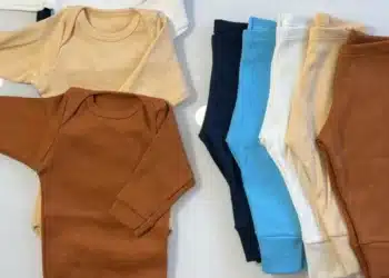 Kit enxoval para gestantes com conjuntos de roupas para bebê em várias cores, incluindo marrom, bege e azul claro.