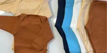 Kit enxoval para gestantes com conjuntos de roupas para bebê em várias cores, incluindo marrom, bege e azul claro.