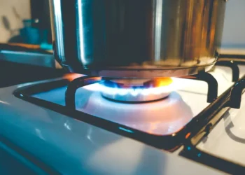 Chama de gás acesa com panela em fogão de cozinha, representando o benefício do gás de cozinha gratuito.
