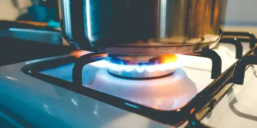 Chama de gás acesa com panela em fogão de cozinha, representando o benefício do gás de cozinha gratuito.