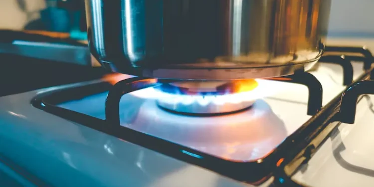 Chama de gás acesa com panela em fogão de cozinha, representando o benefício do gás de cozinha gratuito.