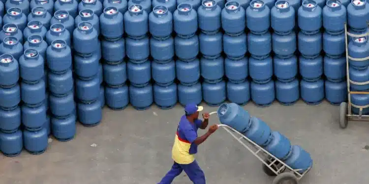 Homem transportando botijões de gás em meio a um grande estoque, simbolizando a distribuição do Vale Gás junto ao Bolsa Família.