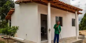 Homem em frente à casa simples recém-construída no interior da Bahia