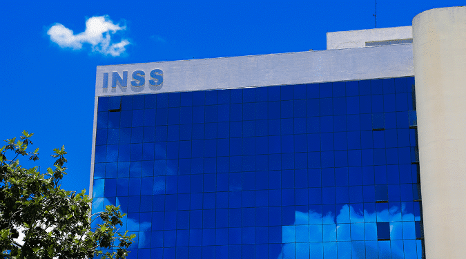 Edifício do INSS refletido em vidro, tema: mais de 600 mil aposentados podem perder dinheiro por não assinar acordo.