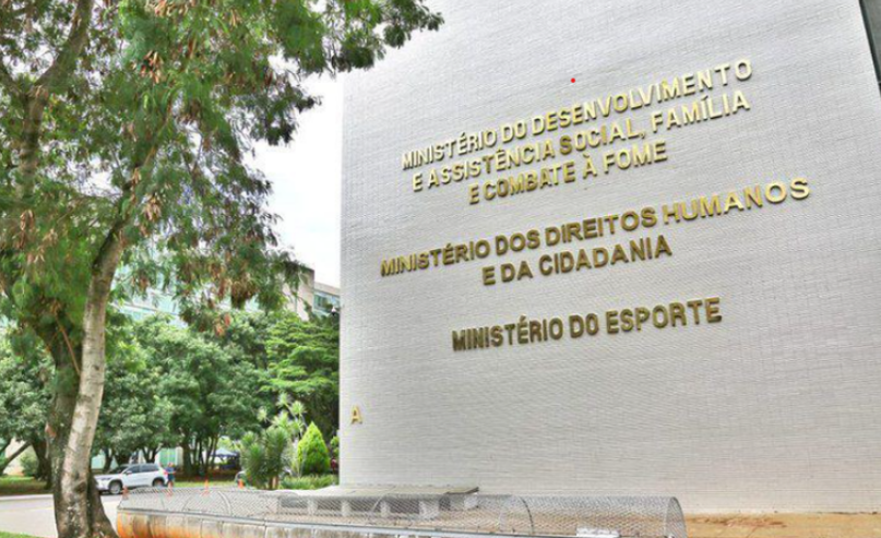 Fachada do Ministério do Desenvolvimento Social e Combate à Fome com alerta urgente sobre visitas domiciliares.