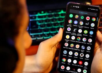 Criança segurando celular com aplicativos visíveis, representando uso excessivo de telas.