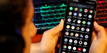 Criança segurando celular com aplicativos visíveis, representando uso excessivo de telas.