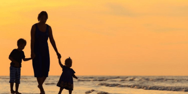 Mulher com seus filhos na praia, simbolizando o conceito de mulheres chefes de família.