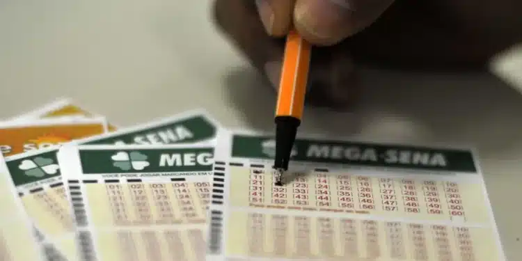 Pessoa preenchendo um bilhete da Mega-Sena com caneta laranja.