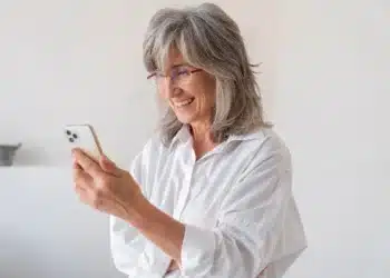 Pessoa sorrindo ao realizar a prova de vida digital do INSS, usando smartphone.