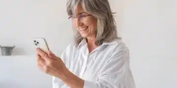 Pessoa sorrindo ao realizar a prova de vida digital do INSS, usando smartphone.