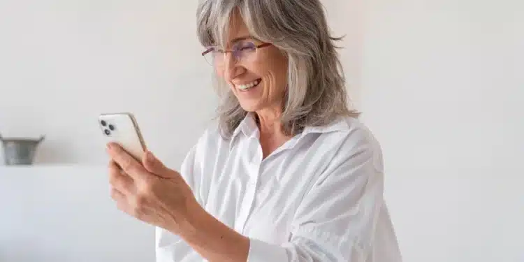 Pessoa sorrindo ao realizar a prova de vida digital do INSS, usando smartphone.