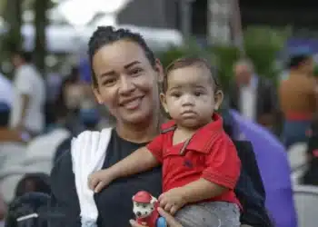 Mãe segurando seu filho durante evento, ilustrando o programa Mães de Pernambuco.