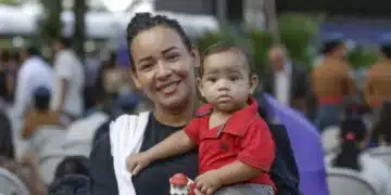 Mãe segurando seu filho durante evento, ilustrando o programa Mães de Pernambuco.