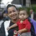 Mãe segurando seu filho durante evento, ilustrando o programa Mães de Pernambuco.