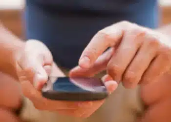 Pessoa consultando o celular para obter informações sobre o Vale Gás 2025.