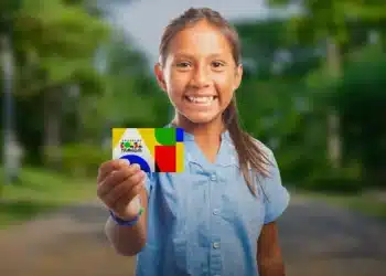 Criança sorrindo e segurando o cartão do Bolsa Família, representando a saída de famílias do programa como um sinal positivo de ascensão social