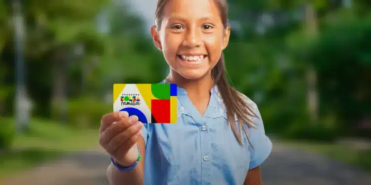 Criança sorrindo e segurando o cartão do Bolsa Família, representando a saída de famílias do programa como um sinal positivo de ascensão social