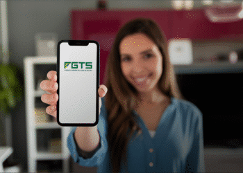 Mulher sorridente mostrando a tela do celular com o logotipo do FGTS.