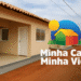 Linha de casas populares recém-construídas do programa Minha Casa Minha Vida em Corumbá, com logo oficial do programa.