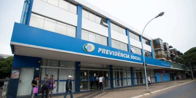 Fachada de uma agência do INSS com pessoas em frente ao prédio.