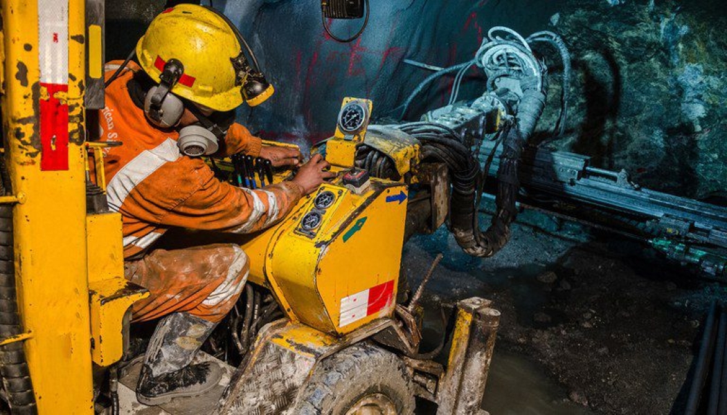 Trabalhador utilizando uma máquina em mina subterrânea, representando atividades com exposição a agentes nocivos, como mineradores, que têm direito à aposentadoria antecipada.