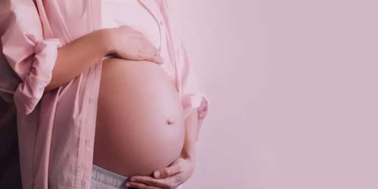 Imagem de mulher grávida, com mãos sobre a barriga, simbolizando proteção e apoio à licença-maternidade no Brasil.