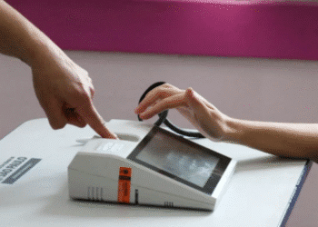 Imagem de uma pessoa interagindo com um dispositivo biométrico em uma mesa.