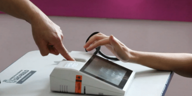 Imagem de uma pessoa interagindo com um dispositivo biométrico em uma mesa.