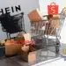 Alerta para compras na Shein, Shopee, Mercado Livre e AliExpress, com caixas de produtos em uma loja virtual.