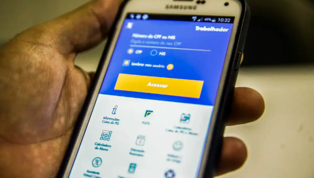 Mão segurando um smartphone com tela do aplicativo FGTS aberta.