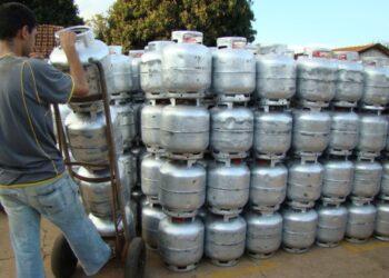 Imagem de um trabalhador retirando um botijão de gás de uma pilha, representando a distribuição gratuita pelo novo programa.