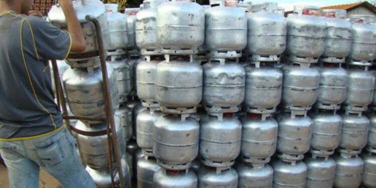 Imagem de um trabalhador retirando um botijão de gás de uma pilha, representando a distribuição gratuita pelo novo programa.