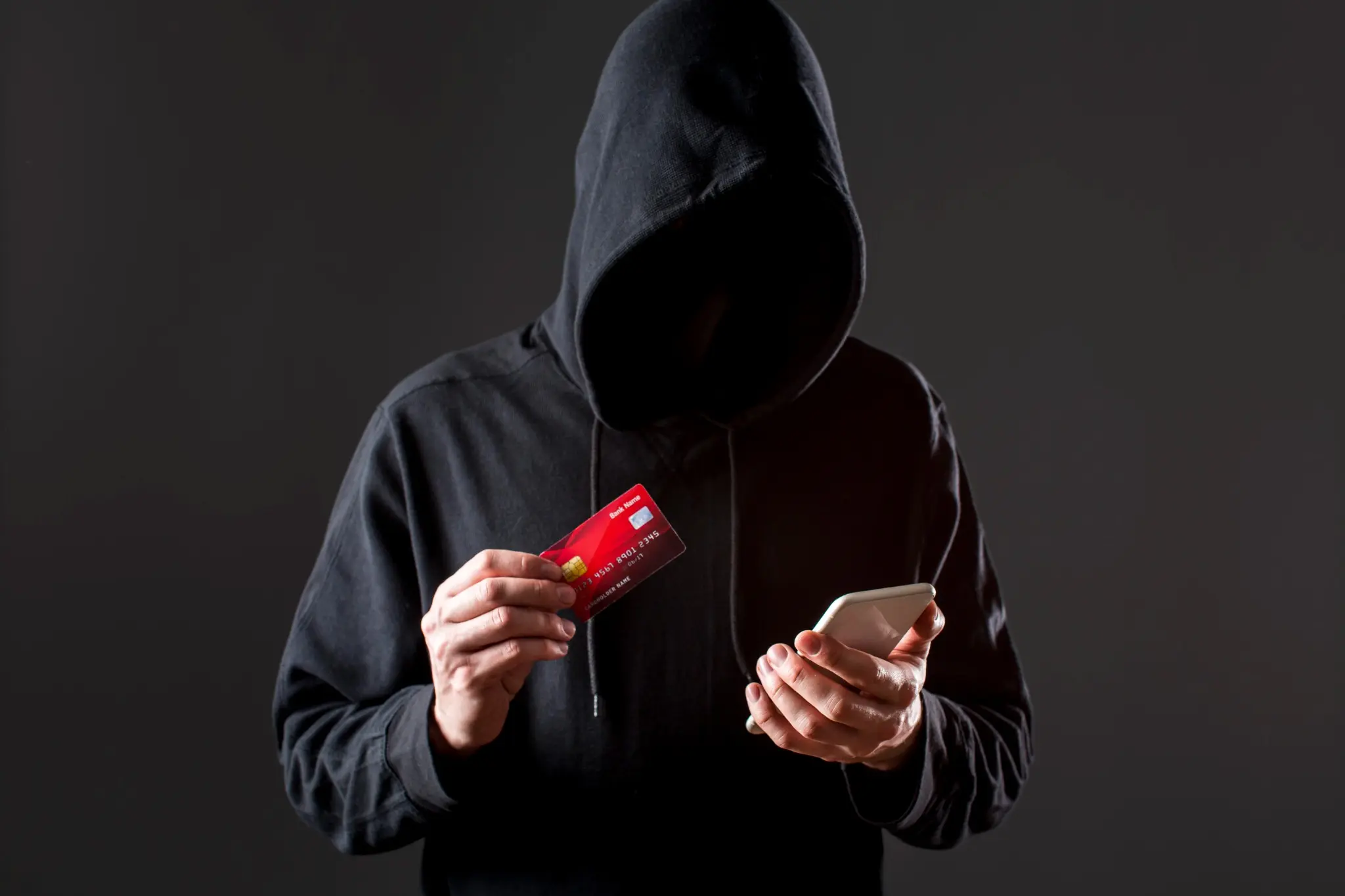 Dicas de segurança: hacker com cartão de crédito e smartphone, alertando sobre golpes online. 