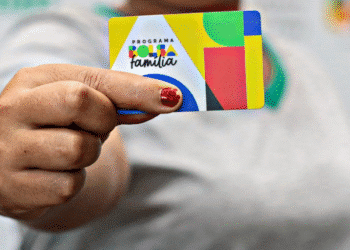 Cartão do Bolsa Família sendo segurado por uma pessoa.