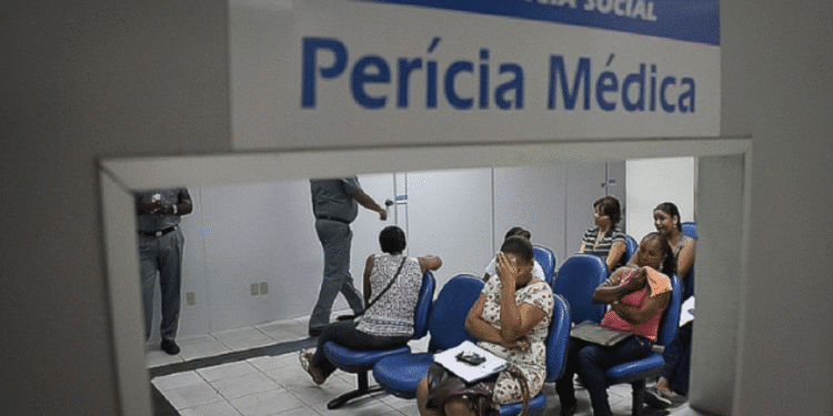 Sala de espera da perícia médica do INSS com pessoas aguardando atendimento.