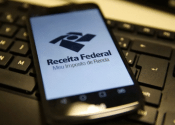 Aplicativo da Receita Federal aberto em celular sobre teclado de computador