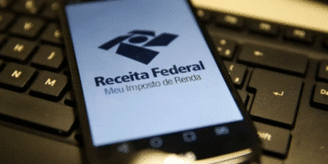 Aplicativo da Receita Federal aberto em celular sobre teclado de computador
