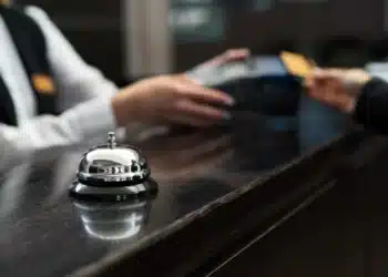 Recepcionista em hotel com uniforme formal, simbolizando mudanças nas regras de hospedagem.