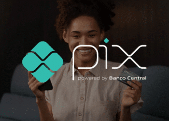 Mulher segurando celular e cartão com logo do Pix ao lado.